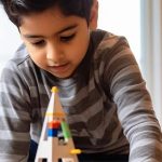 A young child concentrating while building with construction toys